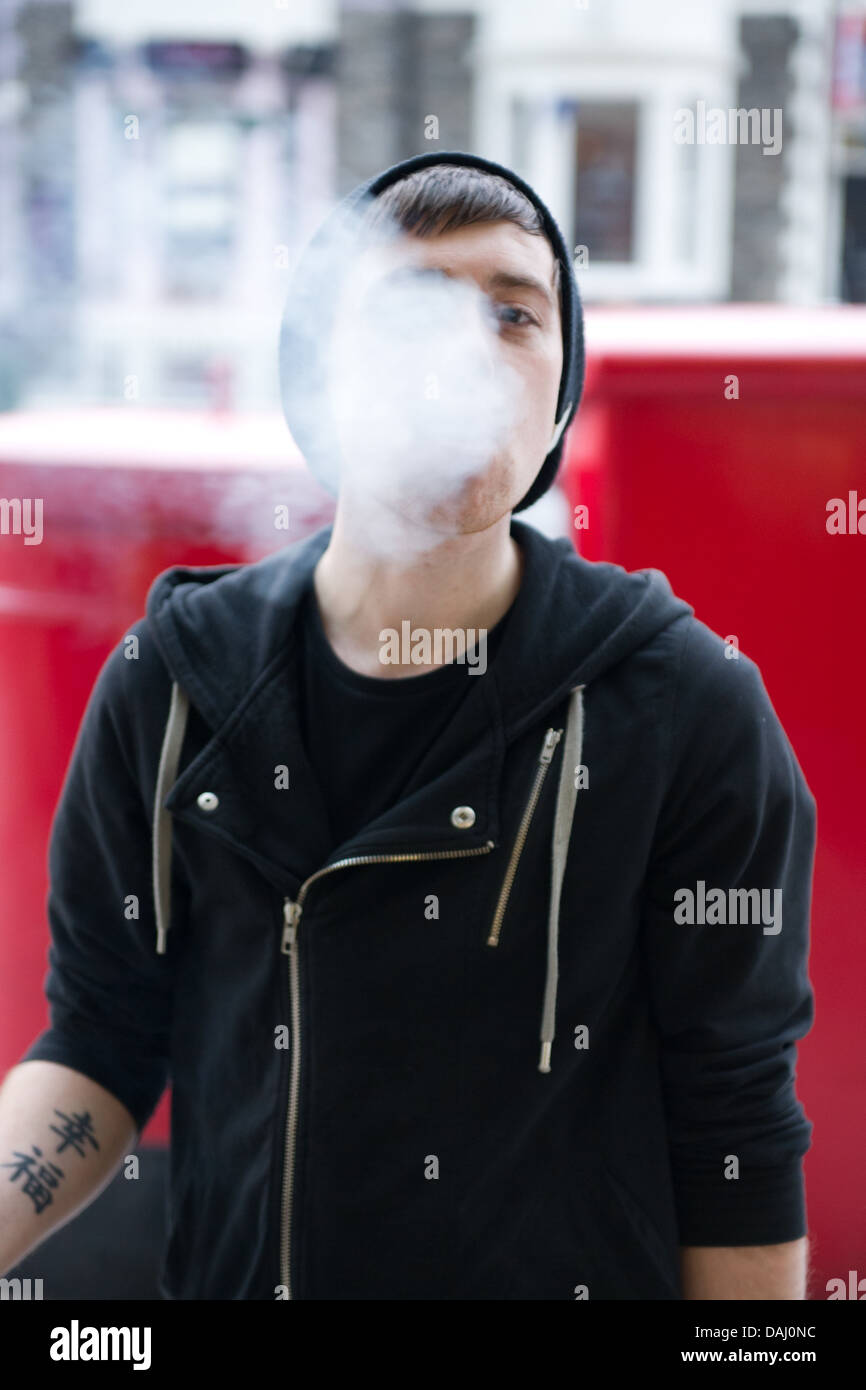Un jeune homme soufflant la fumée de cigarette. Banque D'Images