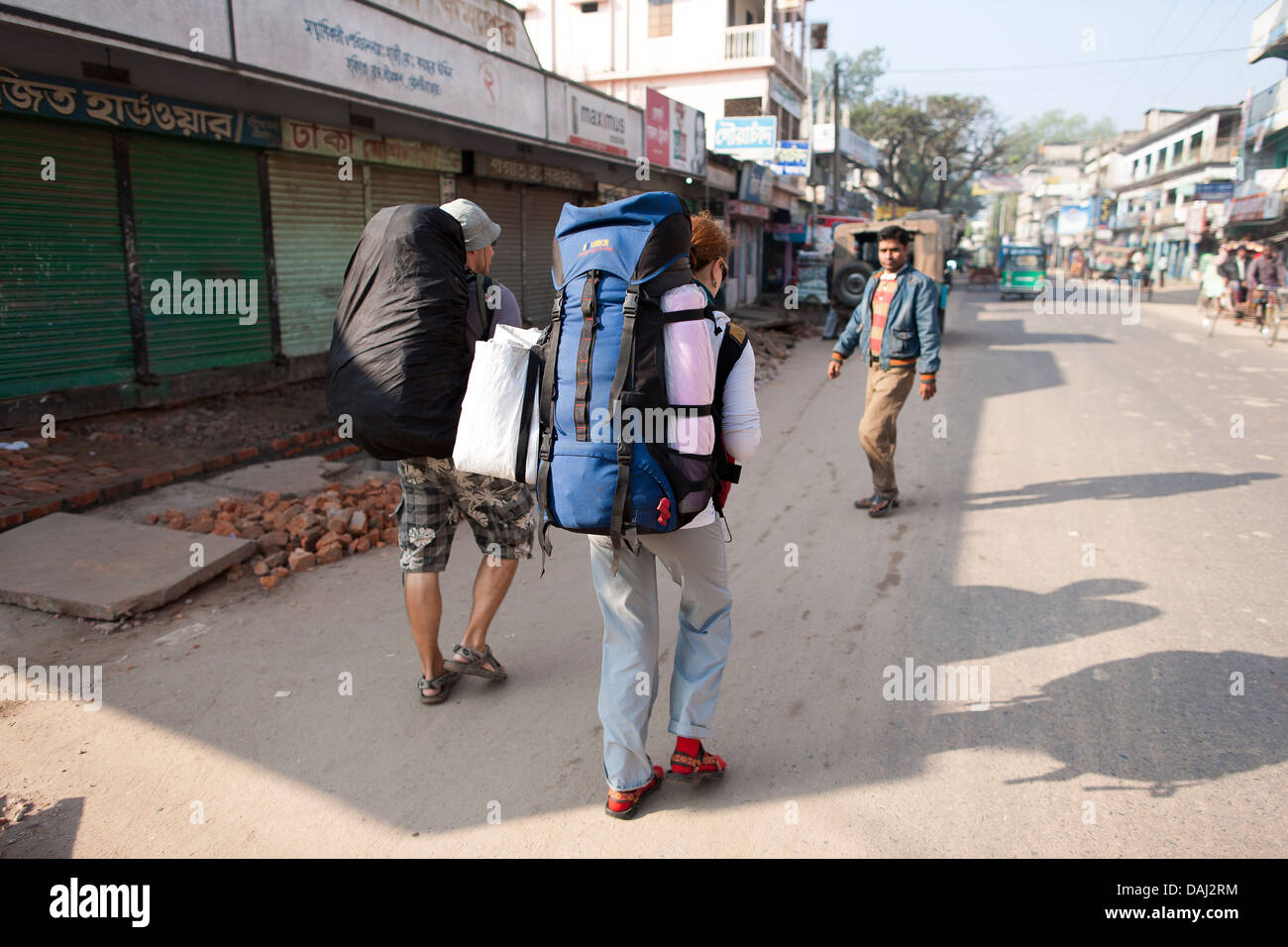 Backpackers, voyageant à travers le Bangladesh et l'Asie du sud-est les rues de Srimongol walkalong pour attraper un bus transportant des packs. Banque D'Images