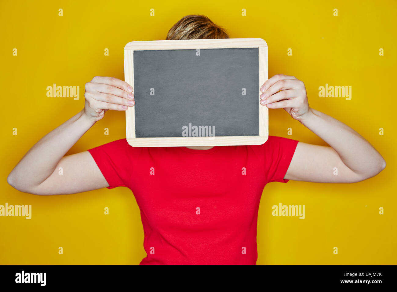 Jeune femme tenant tableau vide en face de son visage Banque D'Images