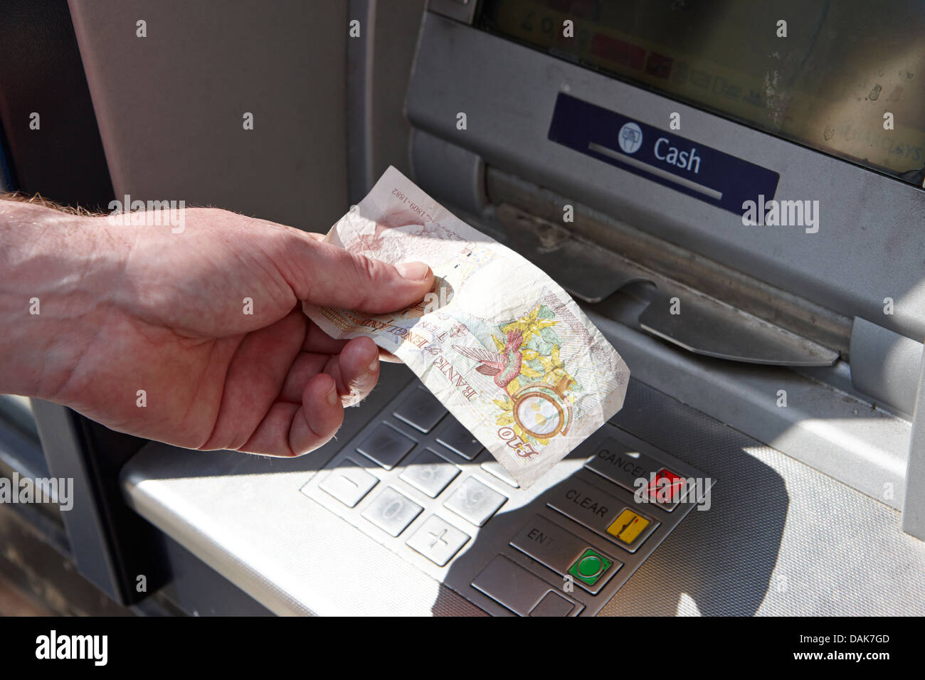 homme exploitant un distributeur automatique de billets retirant un billet unique de dix livres d'argent londres, angleterre royaume-uni Banque D'Images