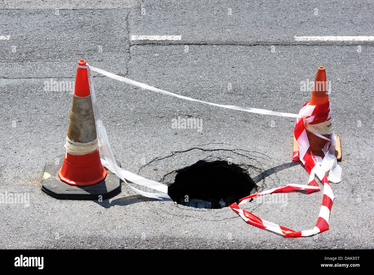 Trou de la route avec des cônes d'avertissement et bande Banque D'Images