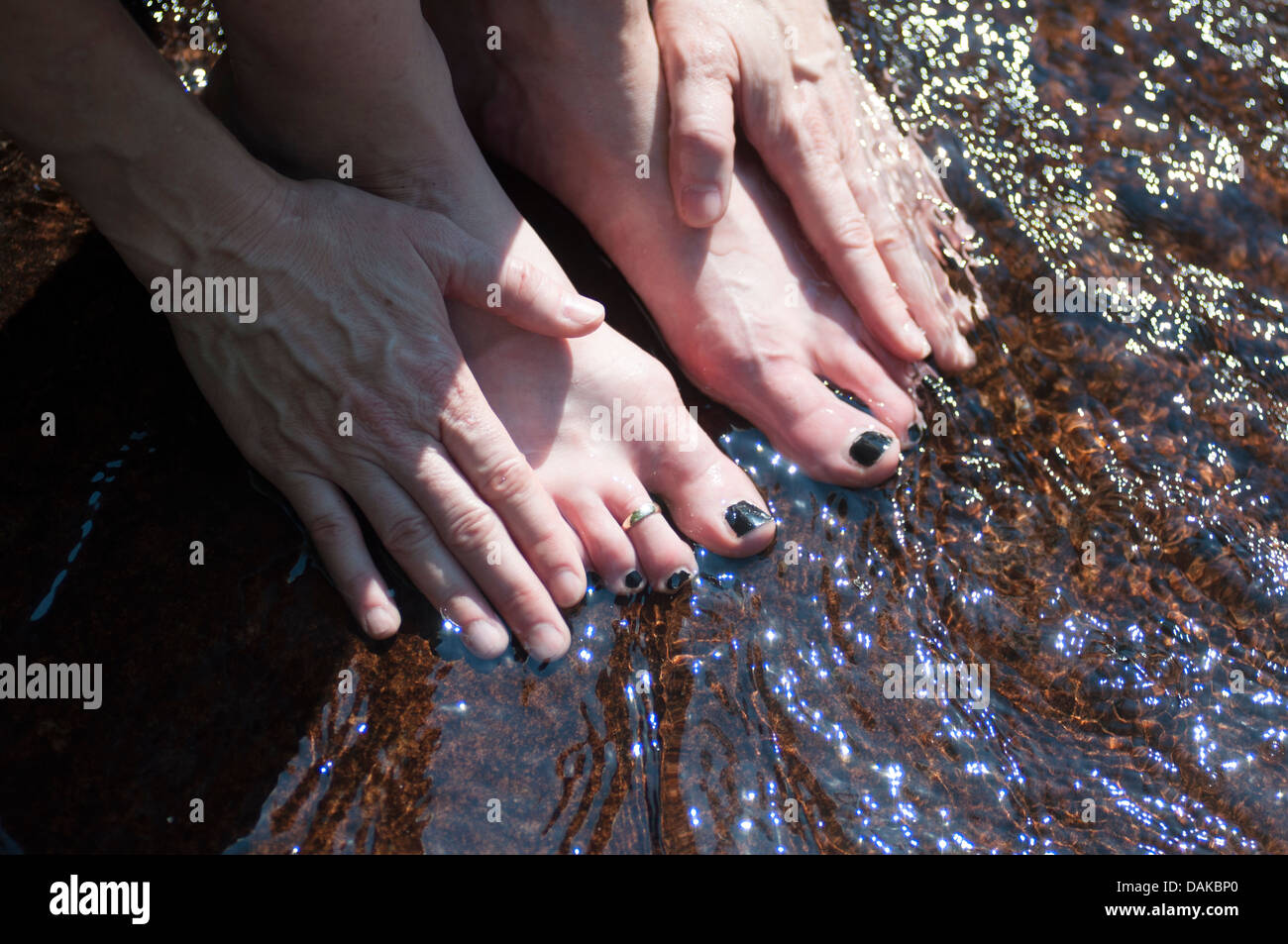 Les mains et les pieds sur un rocher avec de l'eau tournant sur eux. Banque D'Images