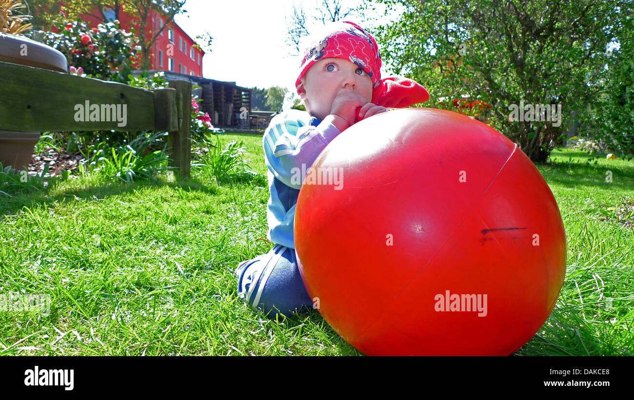 Petit garçon suçant le manche d'une balle hop, Allemagne Banque D'Images