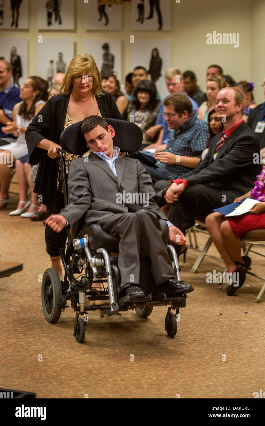 Un fauteuil-bondissent des profils Transition Program (ATP) étudiant poussé par sa mère à la fin de ses études à San Juan Capistrano, CA. Banque D'Images