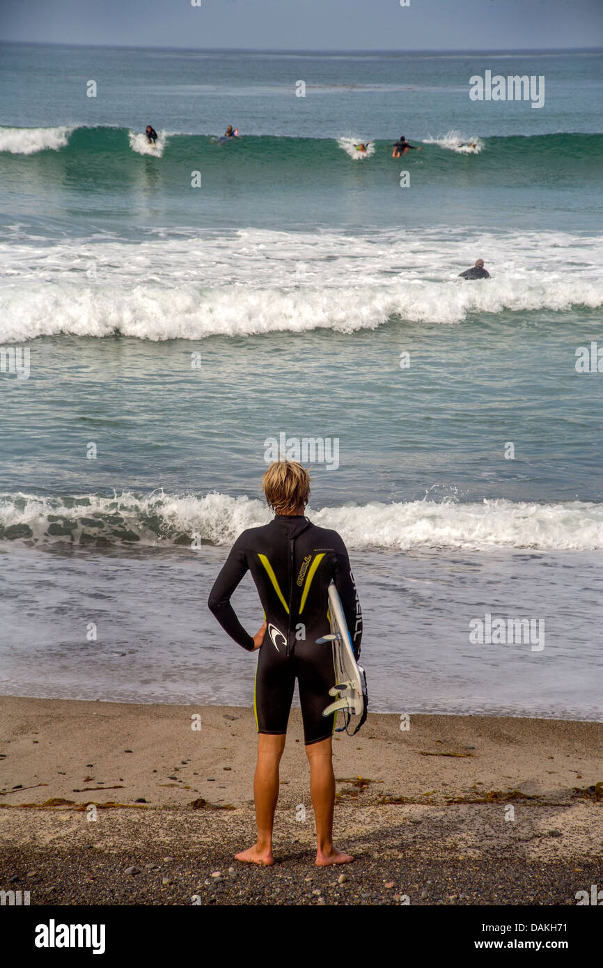 Porter une combinaison de plongée pour l'eau froide, un adolescent membre de la San Clemente, CA, de l'école secondaire de l'équipe de surf se prépare à surfer. Banque D'Images
