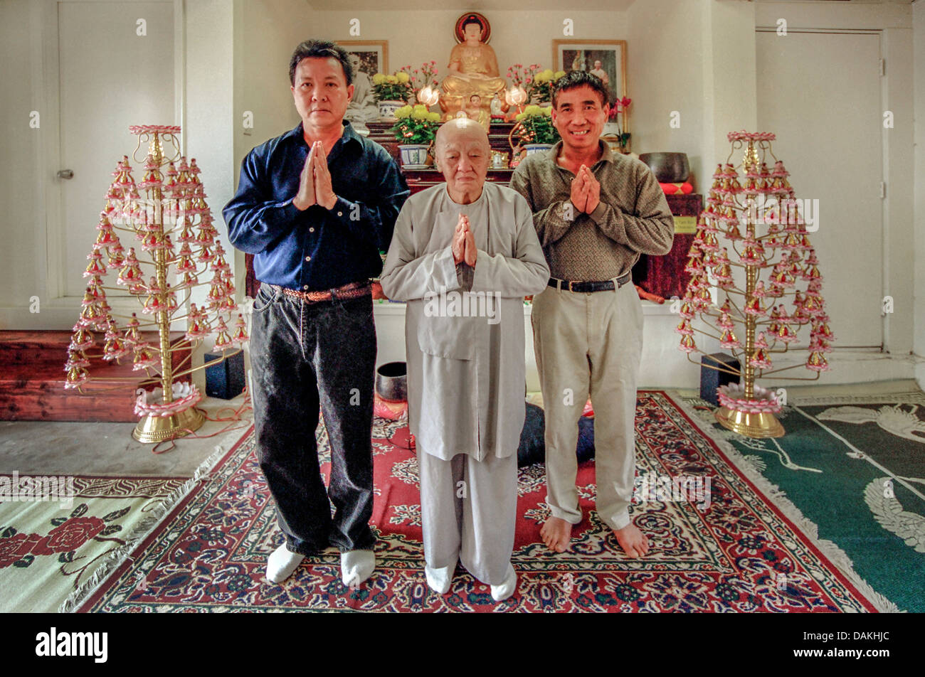 Un prêtre bouddhiste vietnamien prie avec deux jeunes hommes vietnamiens dans son temple de fortune située dans une maison à Santa Ana, CA. Banque D'Images