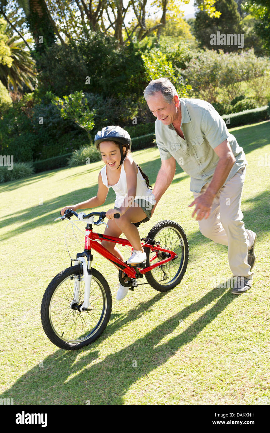 Older Man teaching petite-fille à circuler à bicyclette Banque D'Images