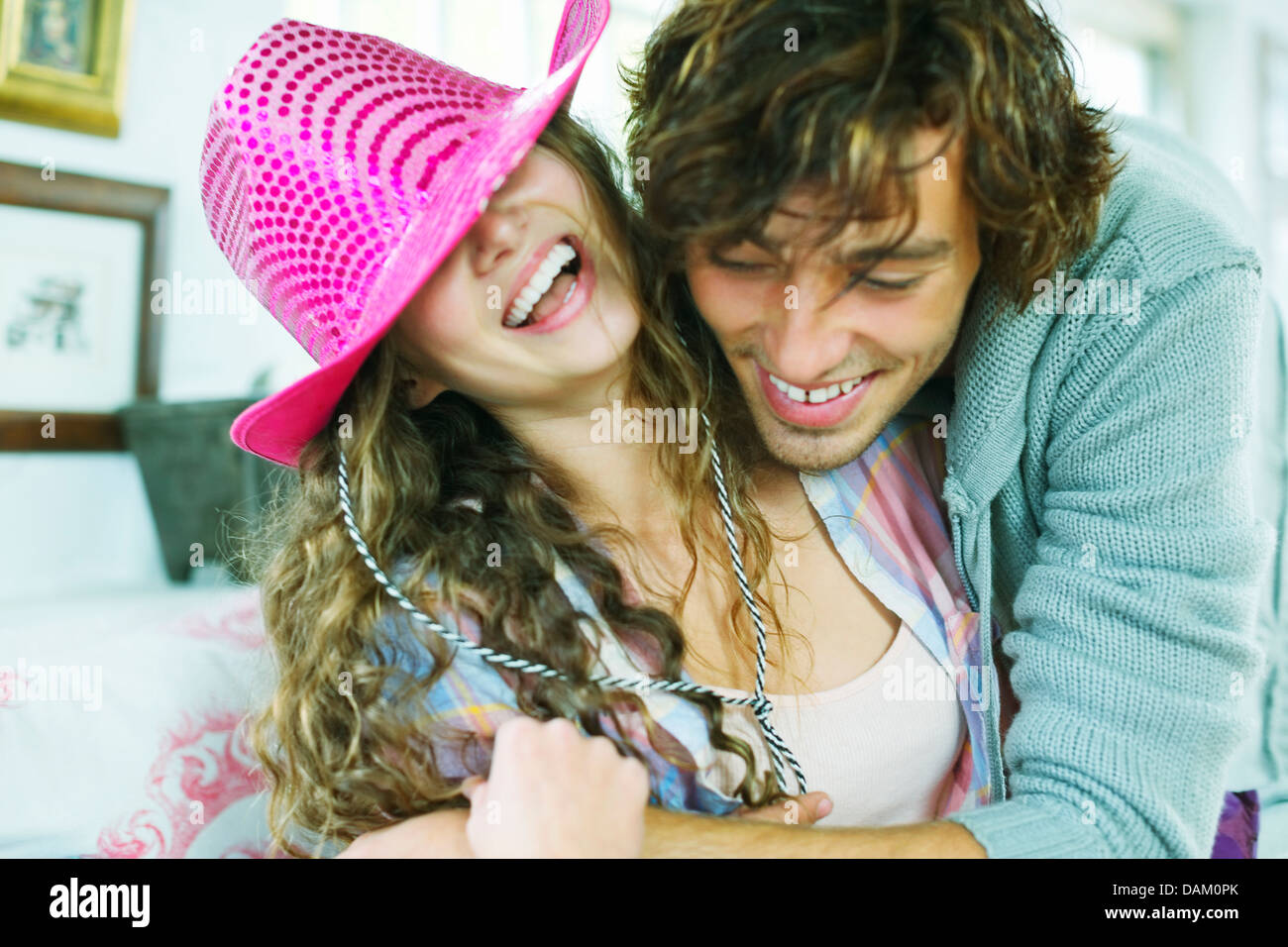 Smiling couple jouant sur canapé Banque D'Images