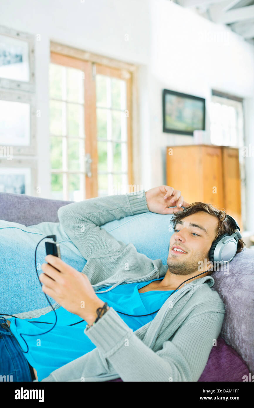 Man listening to headphones on sofa Banque D'Images