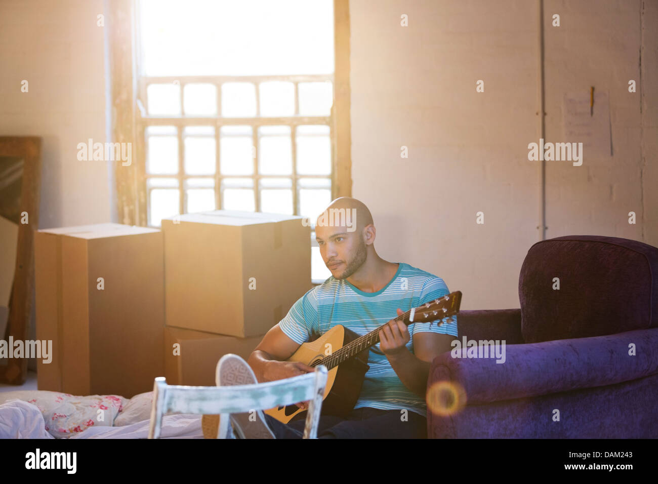 Man playing guitar in new home Banque D'Images