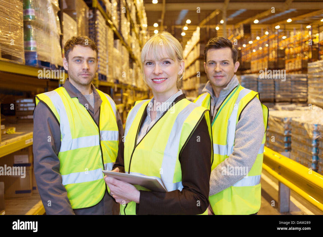 Businesswoman et workers smiling in warehouse Banque D'Images