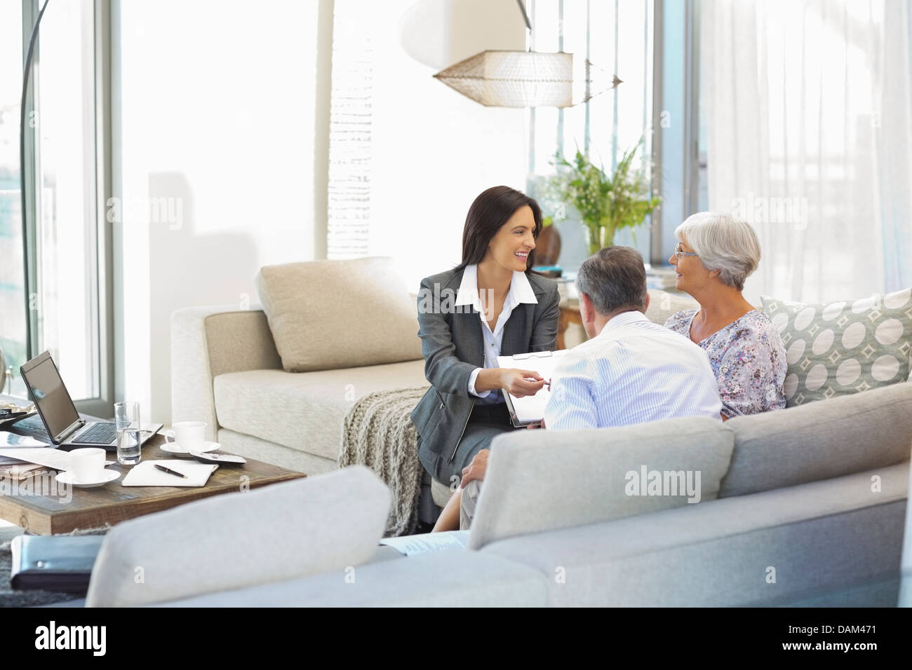 Financial Advisor talking to couple on sofa Banque D'Images