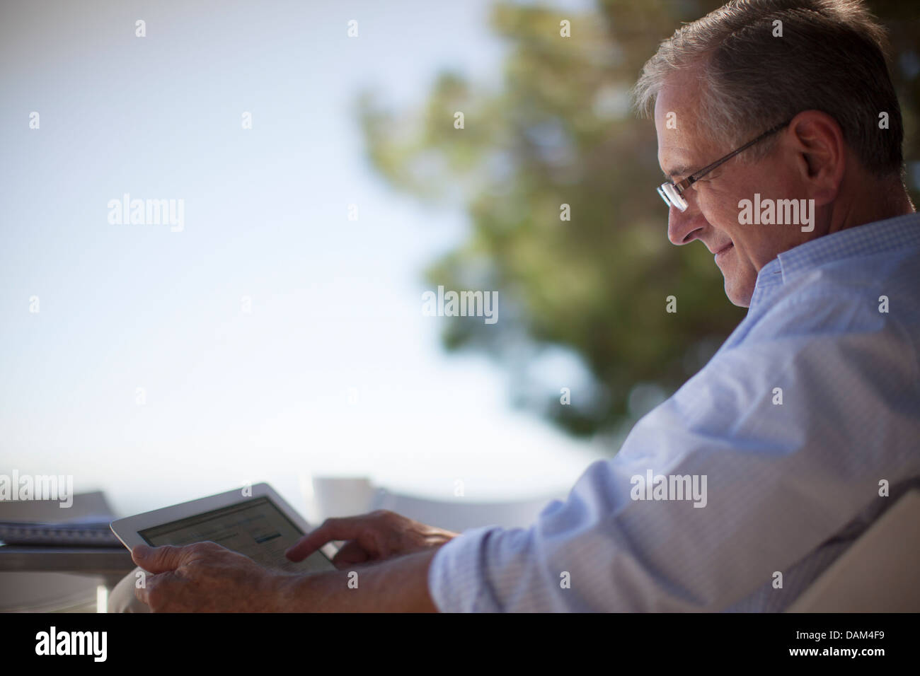 Older Man using tablet computer outdoors Banque D'Images
