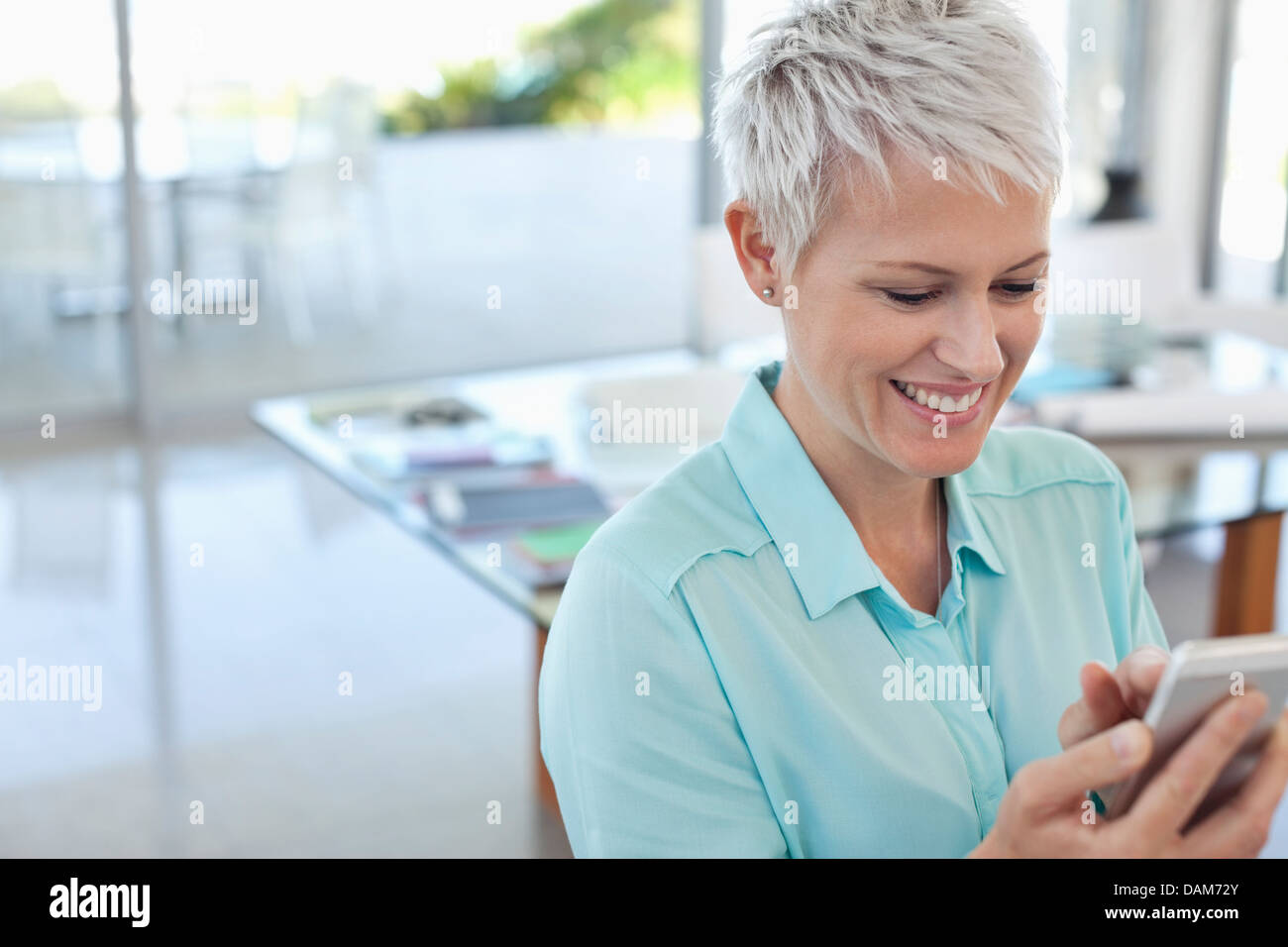 Businesswoman using cell phone in office Banque D'Images