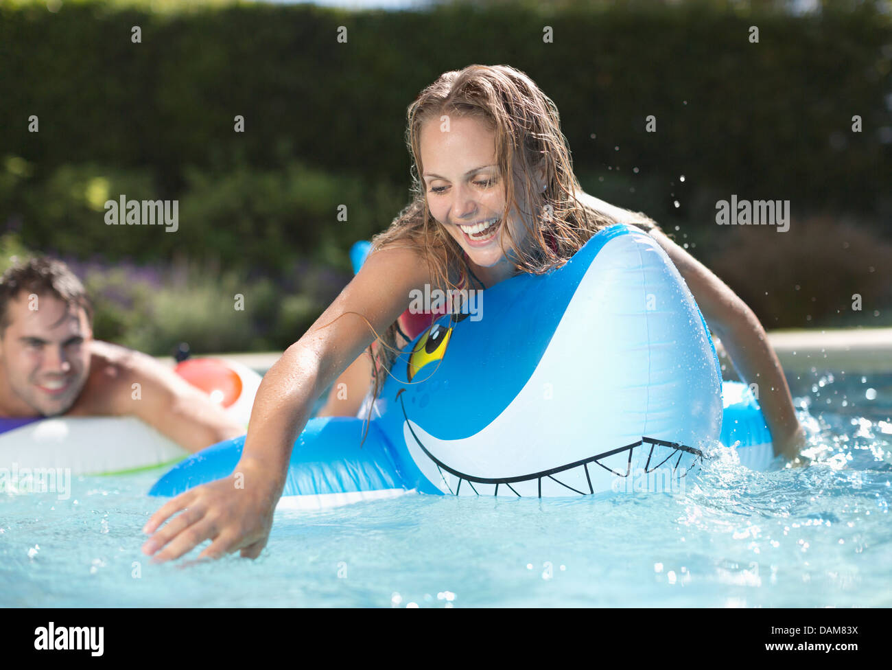 Femme jouant sur inflatable toy in swimming pool Banque D'Images