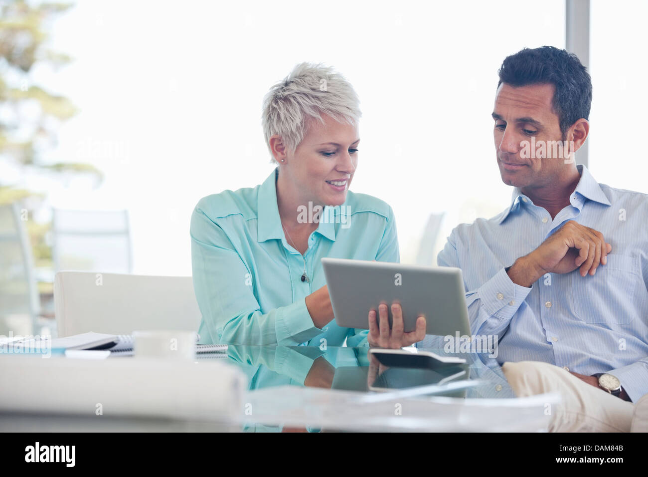 Business people using tablet computer on sofa Banque D'Images