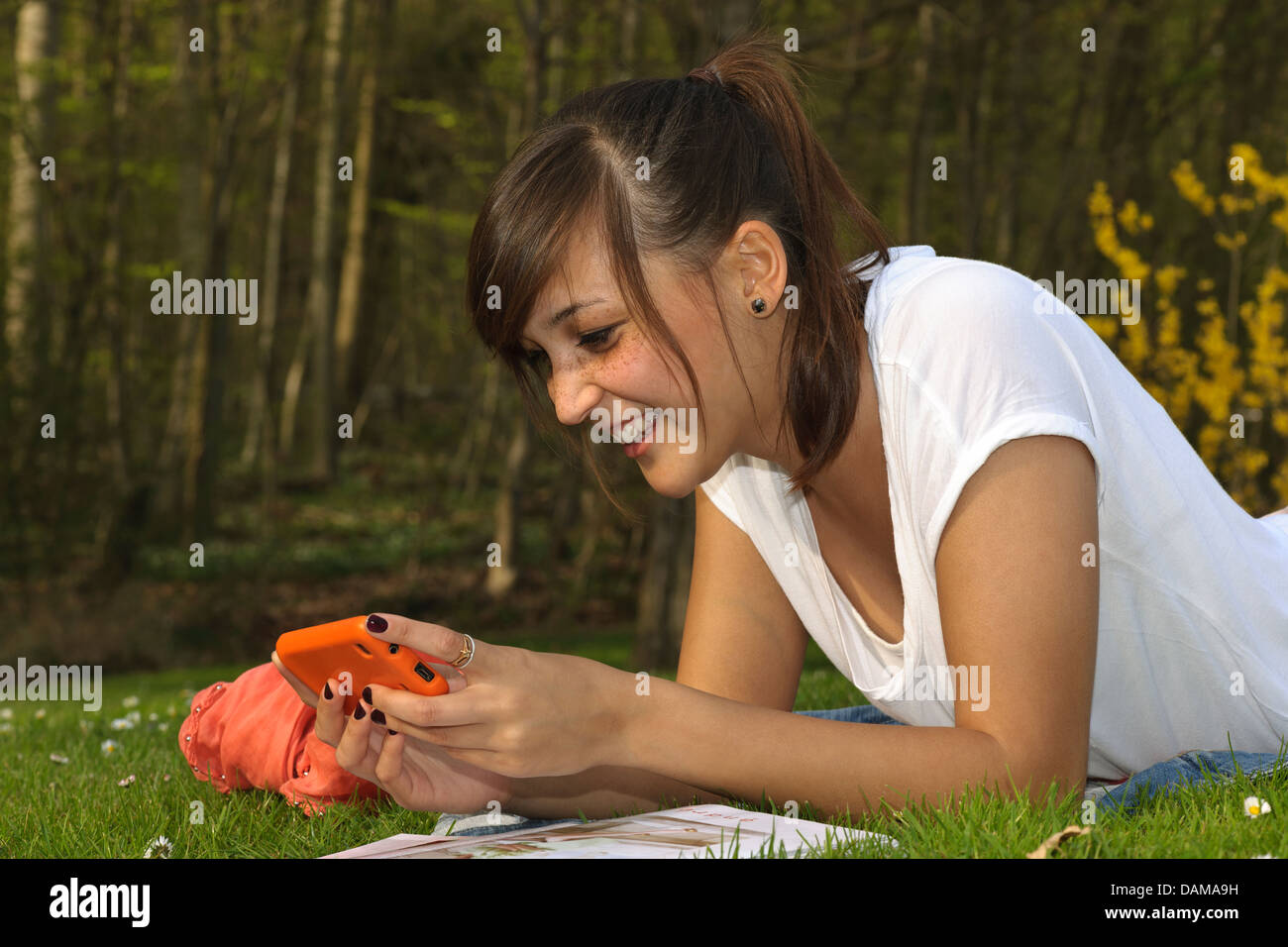 Allemagne, Baden Wuerttemberg, jeune femme de la saisie de sms et de jouer sur le téléphone Banque D'Images