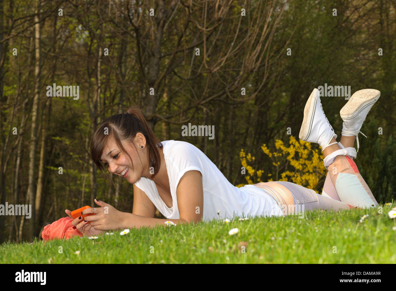Allemagne, Baden Wuerttemberg, jeune femme types de sms et de jouer sur le téléphone Banque D'Images