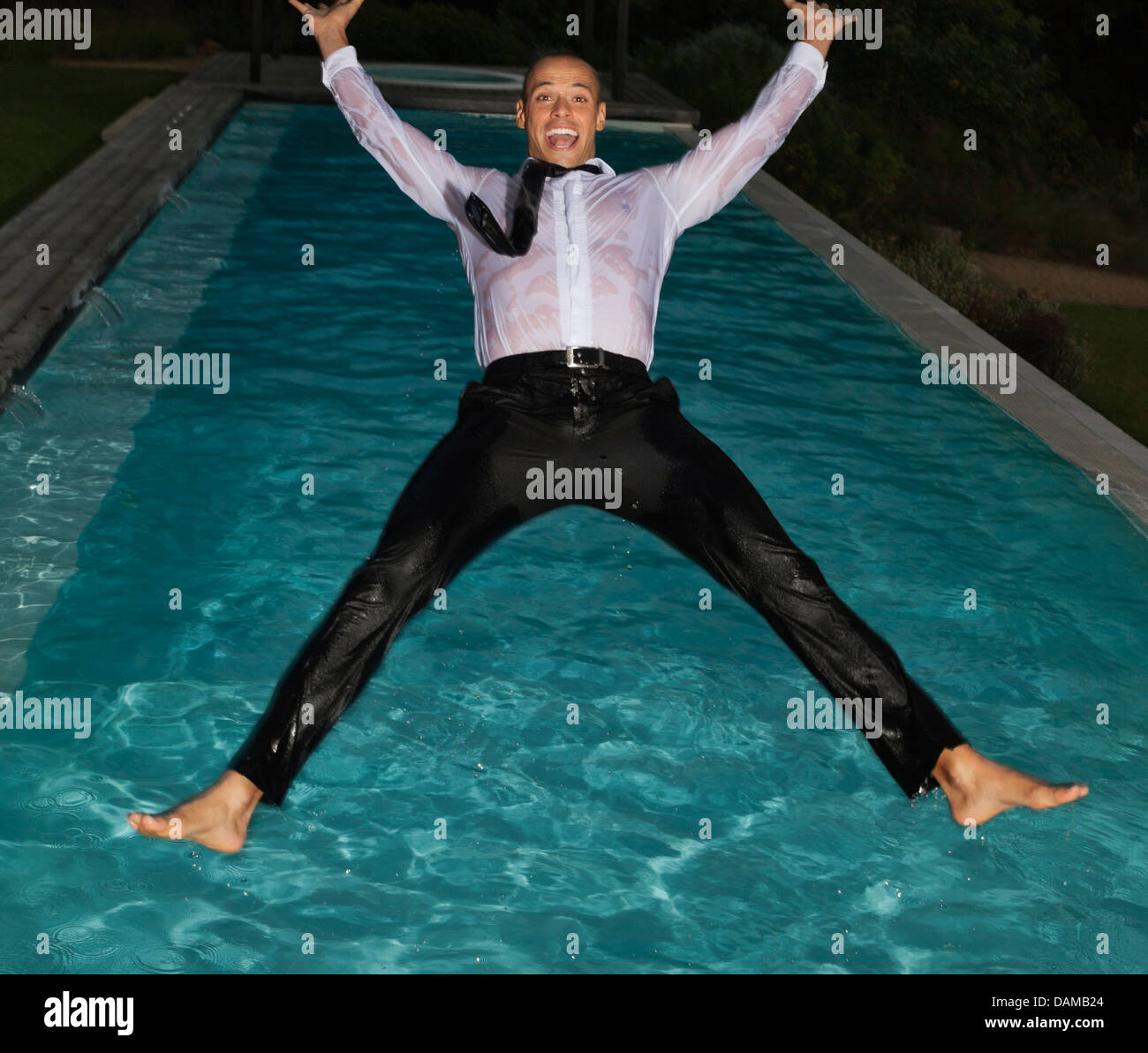 Toute habillée man jumping into swimming pool Banque D'Images