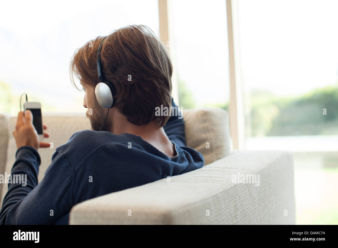 Man listening to headphones on sofa Banque D'Images