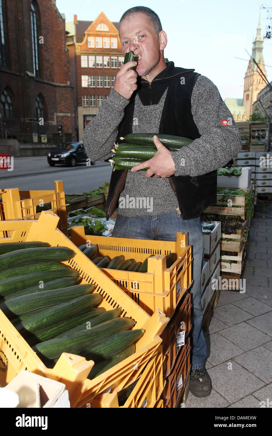 Farmer Rainer Horstmann mange le concombre et donne des légumes comme présente dans le centre-ville de Hambourg, Allemagne, 10 juin 2011. Avec la devise "nos légumes sont propres et sans danger" les agriculteurs et les vendeurs veulent point à la situation dévastatrice dans lequel ils se trouvent, depuis la bactérie ECEH est répandue. Les avertissements concernant la consommation de tomates, concombres et salades Banque D'Images