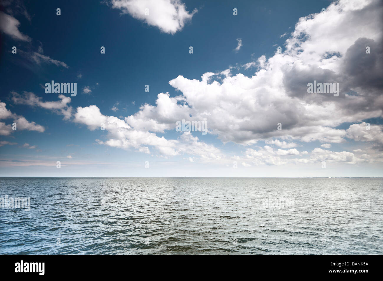 Ciel bleu nuages blancs moelleux au-dessus d'une surface de la mer Banque D'Images