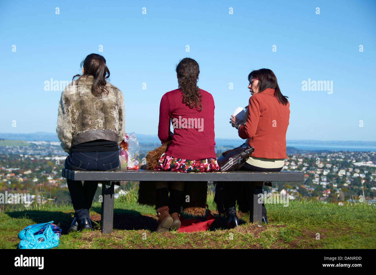Les amis s'assit sur un banc sur le sommet du Mont Eden, Auckland, Nouvelle-Zélande. Banque D'Images