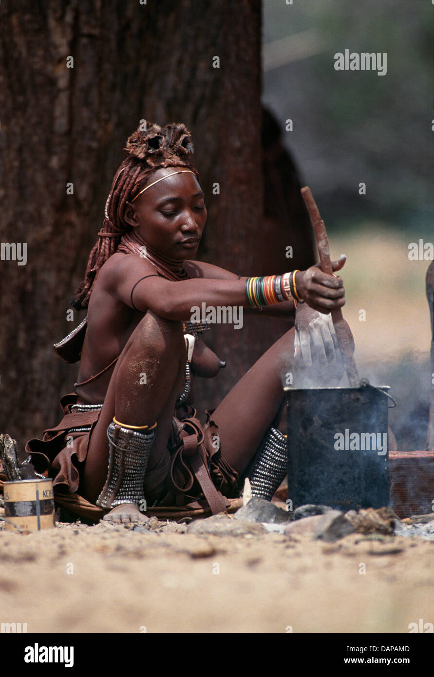 Une femme Himba cuisson sur feu ouvert dans Kaokoland, Namibie Banque D'Images