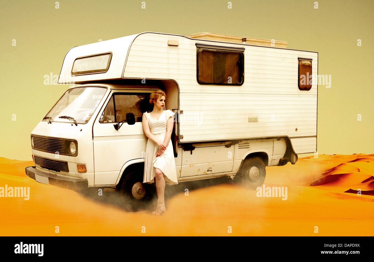 Allemagne, Berlin, young woman standing next to bus camping in desert Banque D'Images