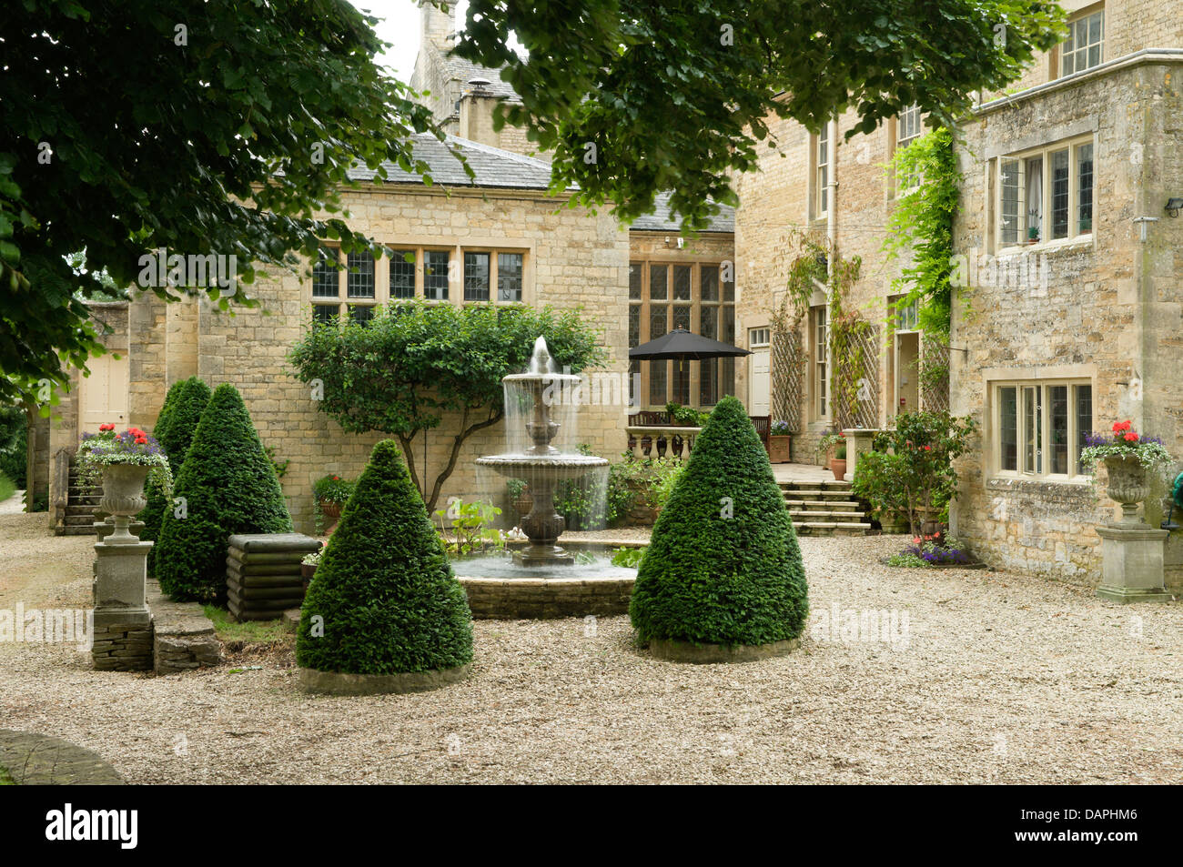 Fontaine à eau et en topiaire cour de Jacobean maison de campagne anglaise, Ampney Park, 17ème siècle en pierre de Cotswold Banque D'Images