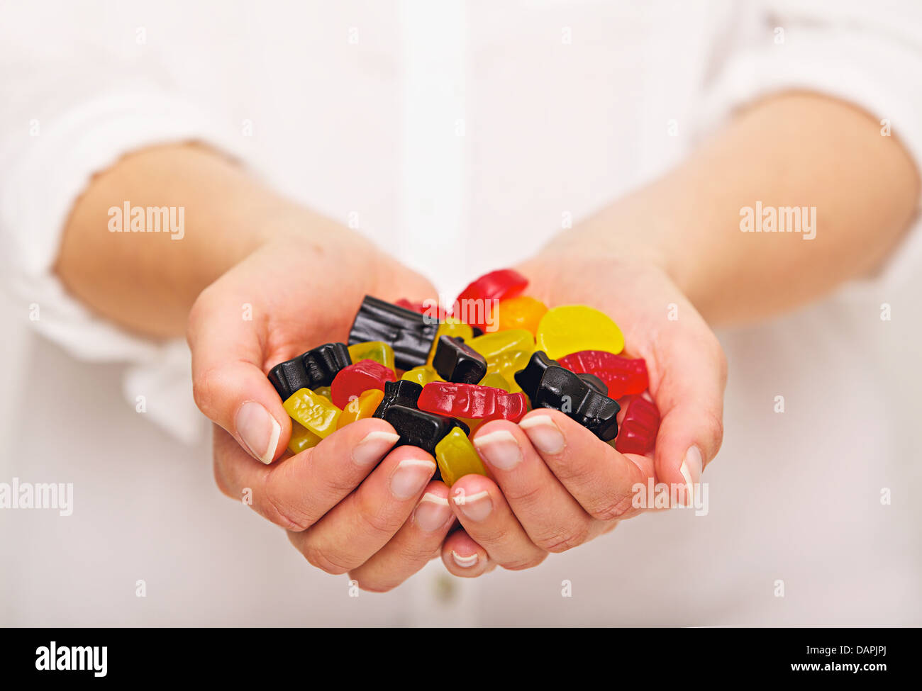 Femme avec une poignée de bonbons multicolores Banque D'Images