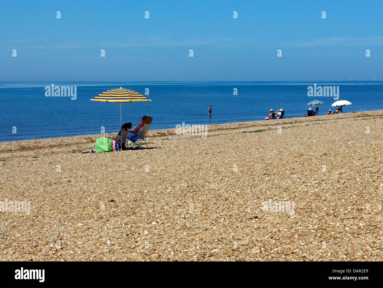 Une vue sur la plage avec des parasols et des personnes lors d'une journée ensoleillée à King's Lynn, Norfolk, Angleterre, Royaume-Uni. Banque D'Images