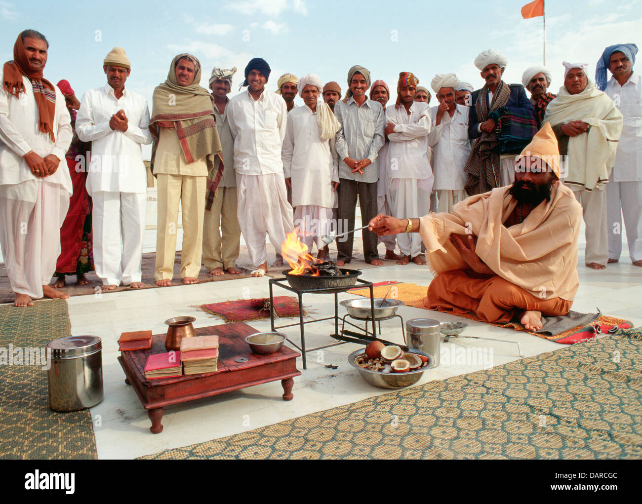 Un ascète hindou appartenant à la secte Bishnoï effectue un rituel du feu. Derrière lui, les fidèles appartenant à la même caste. Banque D'Images