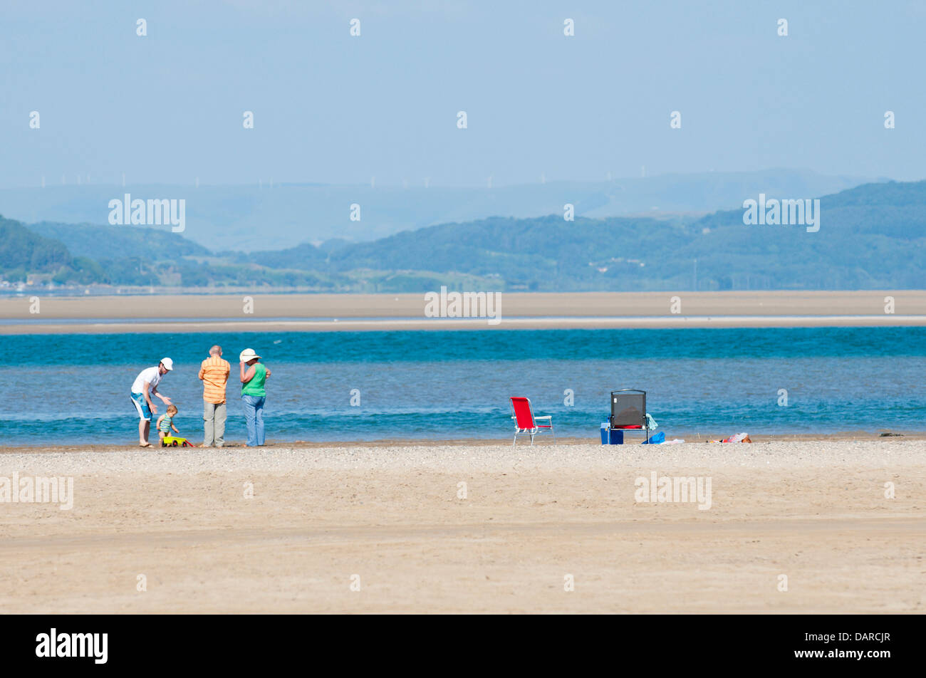 L'estuaire de Dovey/Borth, Ceredigion, pays de Galles, Royaume-Uni. 17 juillet 2013. Une famille jouissent de la liberté et de l'espace. Une étendue de sable plat dur - qui offre un immense parking pour les voitures à 1 € par voiture par jour - dans la Dovey Dyfi (en gallois) Estuaire, fait partie d'une grande surface des eaux côtières soutenue par la campagne du Pays de Galles et du Conseil ainsi que les dunes de sable environnantes offre un magnifique salon pour les gens d'échapper à la vague de chaleur qui a été la Grande-Bretagne torride pendant près de deux semaines. L'accueil cool brise de mer soufflent en provenance de la mer d'Irlande. Crédit photo : Graham M. Lawrence/Alamy Live News. Banque D'Images