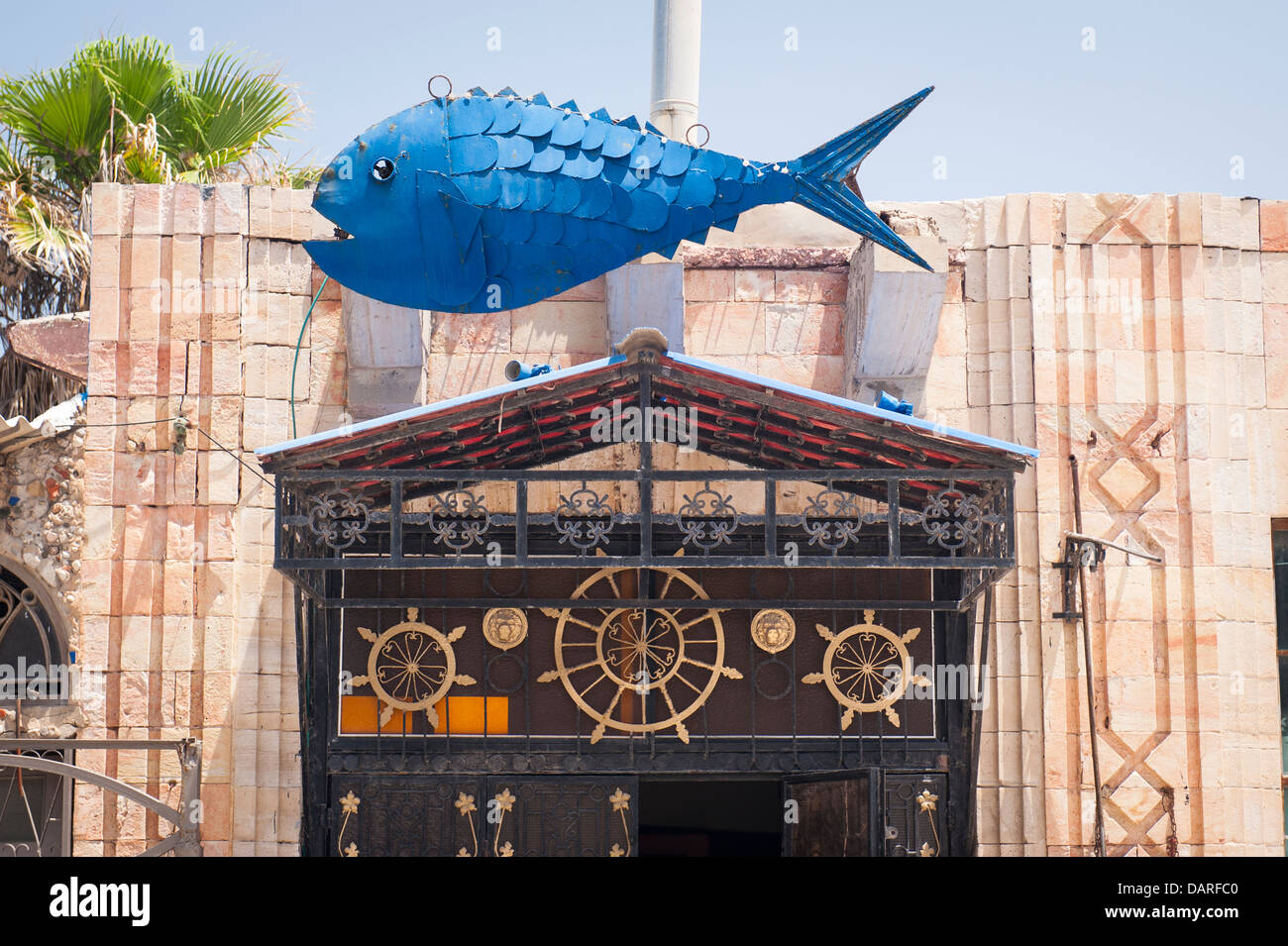 Israël Tel Aviv Vieux Jaffa Yafo cafe bistro restaurant poissons promenade avec le géant bleu métal statue sculpture sur toit quirky fun portail détail Banque D'Images