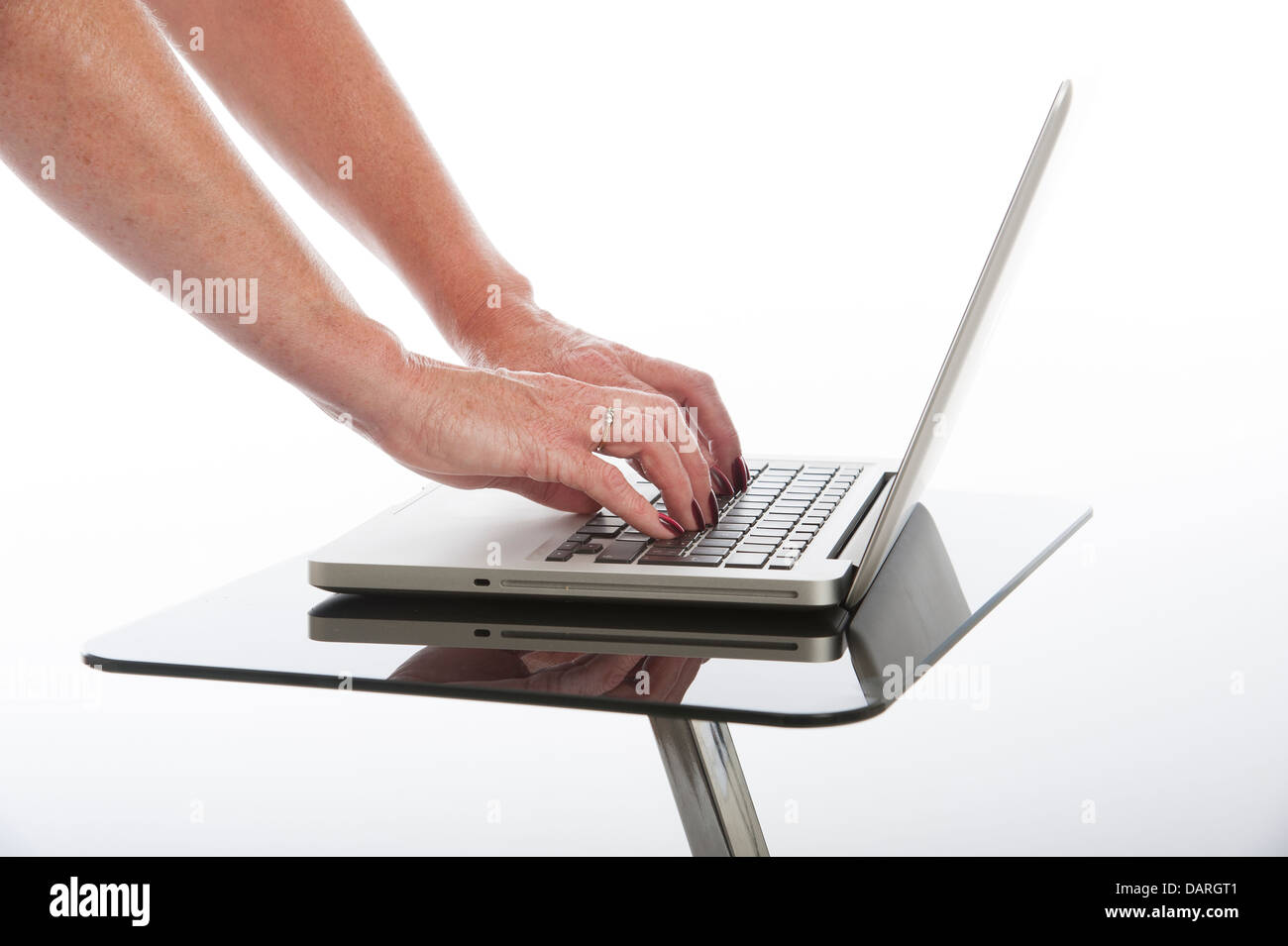 Femme à l'aide d'un ordinateur portable sur une table en verre noir Banque D'Images