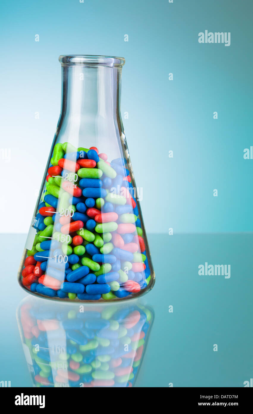 Flacon de laboratoire avec vert bleu et rouge comprimés et comprimés sur bleu Banque D'Images