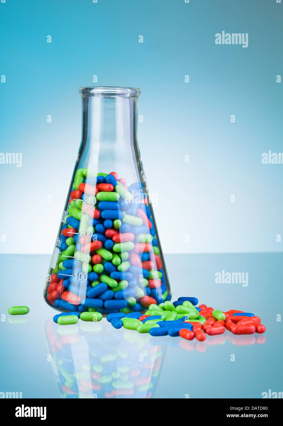 Autre vert bleu et rouge tablet comprimés médicaments sur étiquette bleue de table et en flacon en verre de laboratoire Banque D'Images