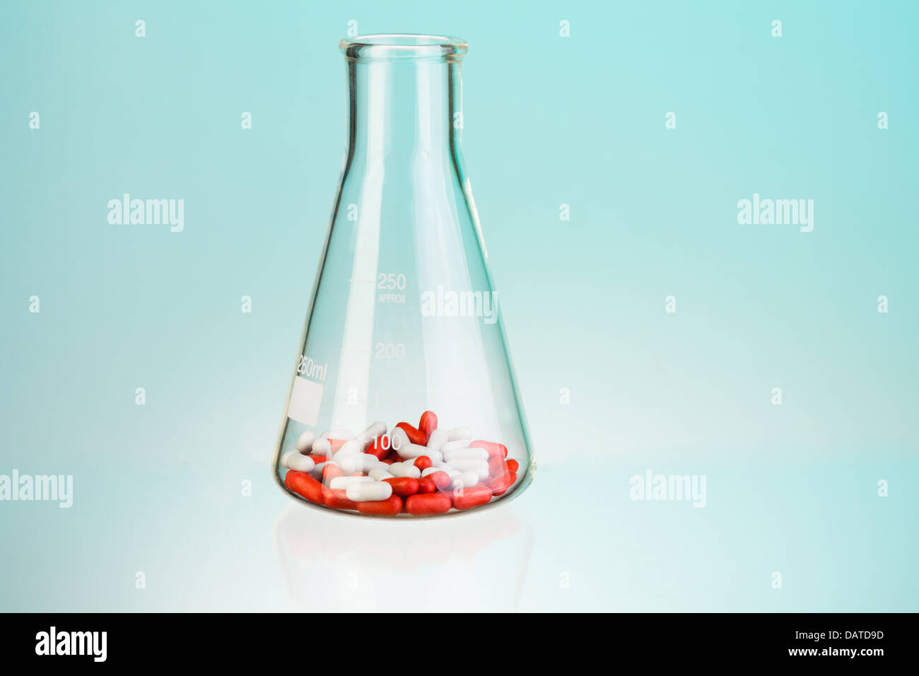 Flacon de laboratoire avec des comprimés blancs et rouges et des pilules sur bleu Banque D'Images