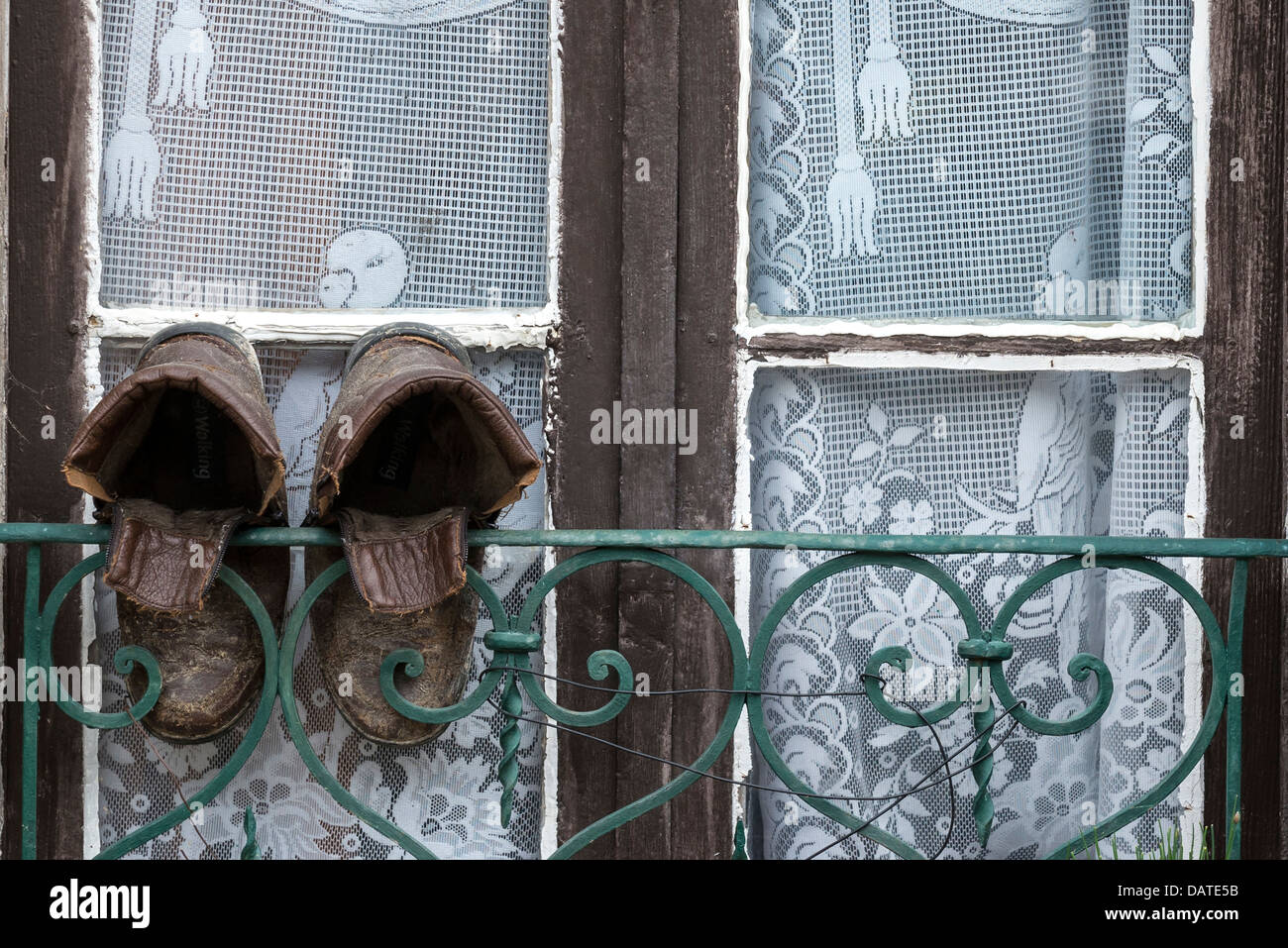 Une vieille paire de bottes en cuir accrochée à une fenêtre avant de sécher Banque D'Images