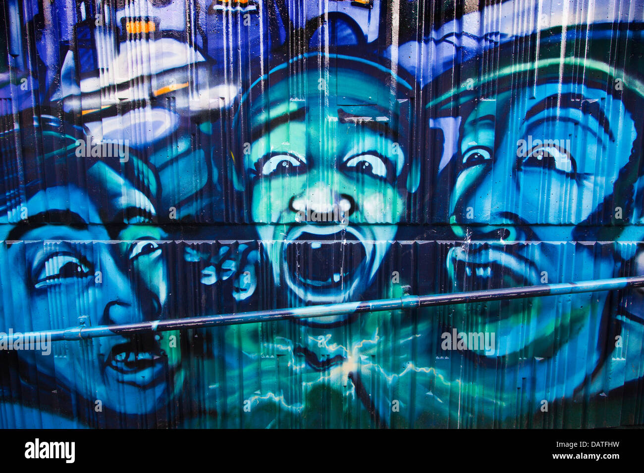 Street art peinture des chefs avec la bouche ouverte pulvérisé sur mur de métro à Sunbury Cross, Surrey, UK. Banque D'Images