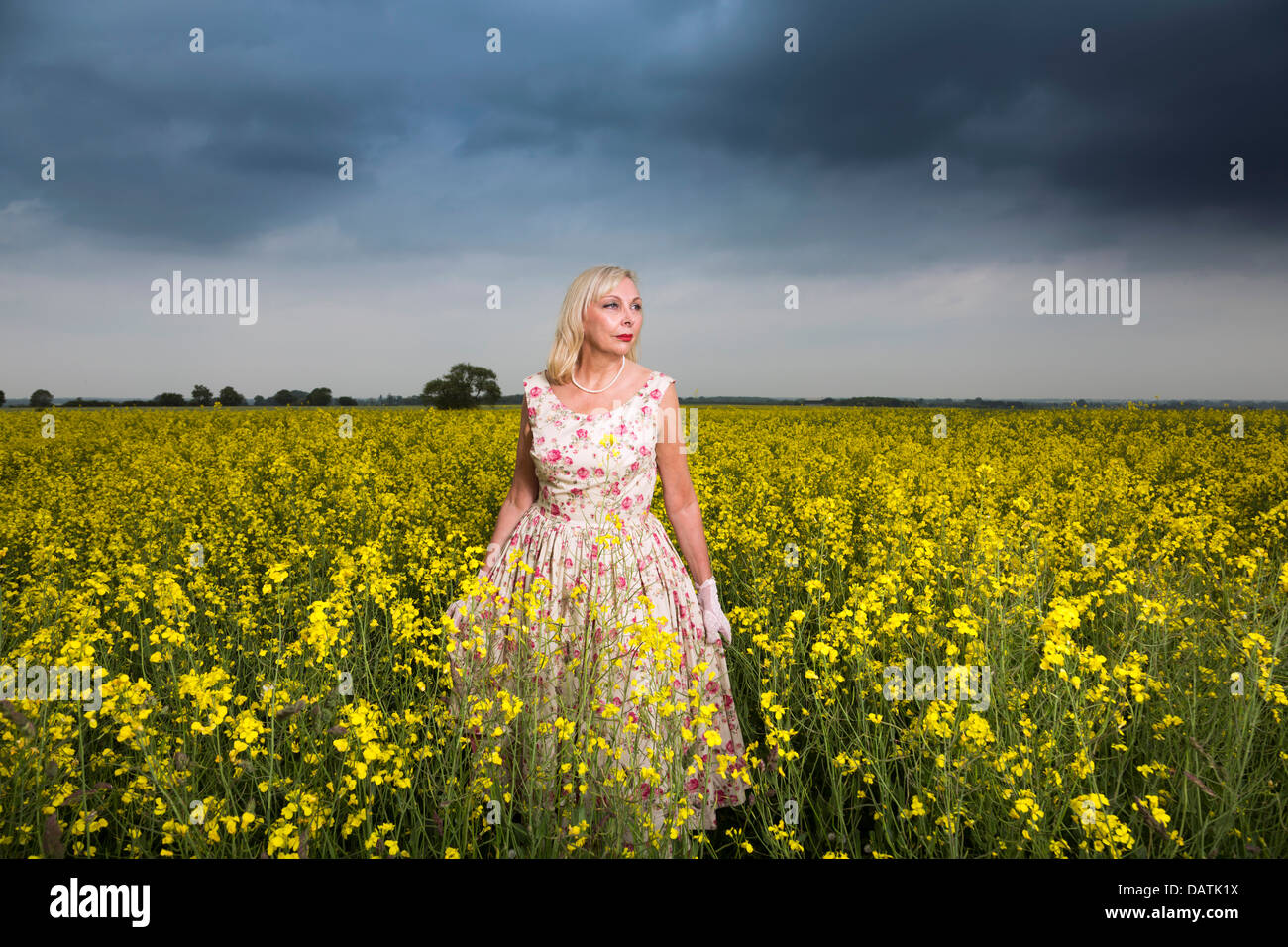 Femme debout dans le champ en pleine campagne avec des cultures oléagineuses Banque D'Images