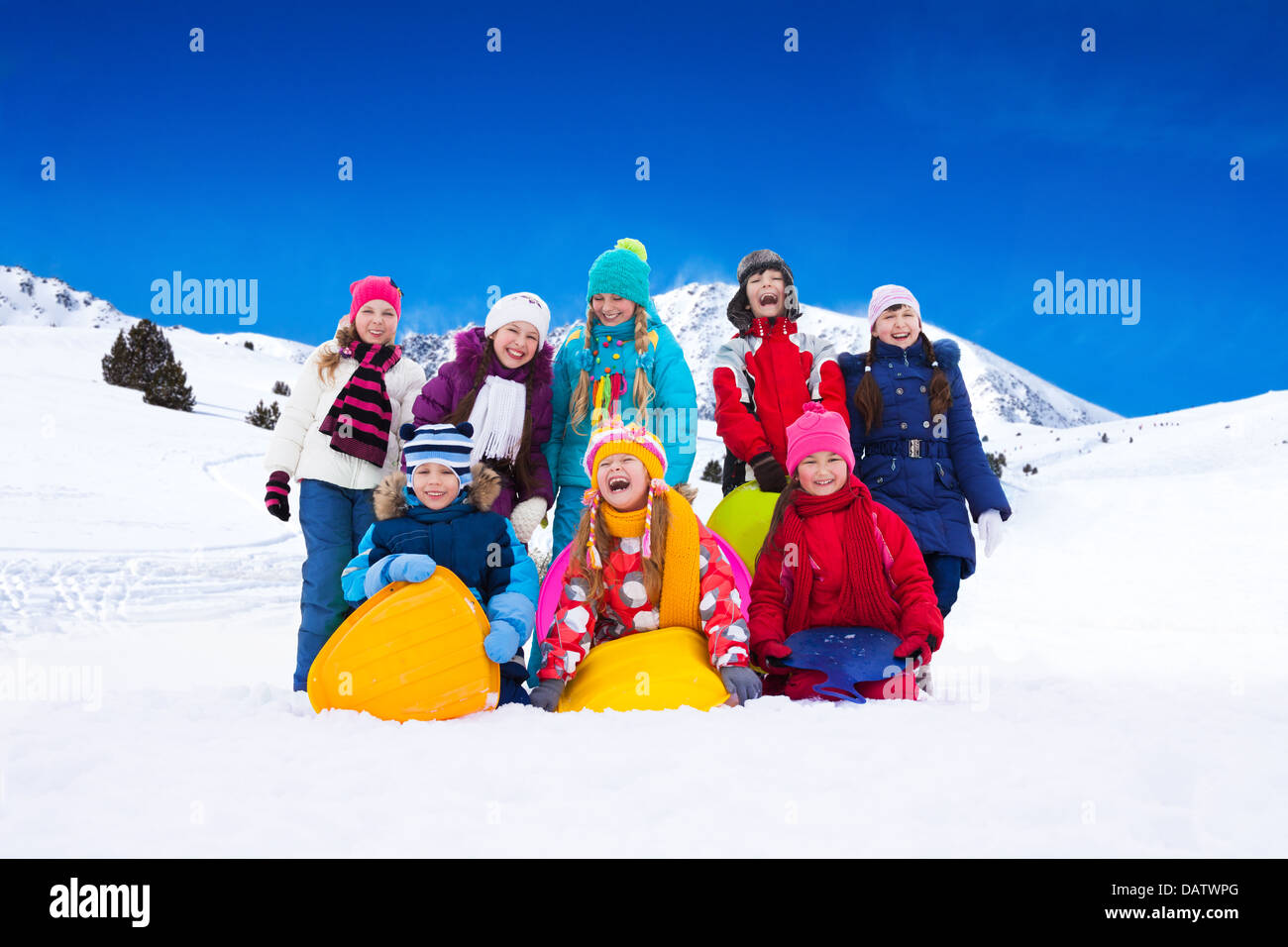 Groupe d'heureux certains garçons et filles à traineau, debout ensemble dans la neige Banque D'Images