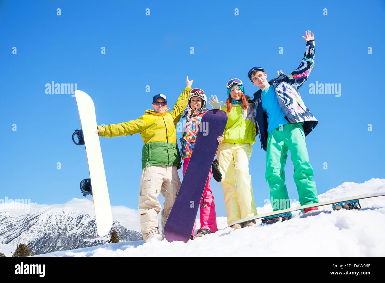 Heureux les hommes et les femmes d'amis stand dans la neige avec les planches du levage et des signes avec la main Banque D'Images