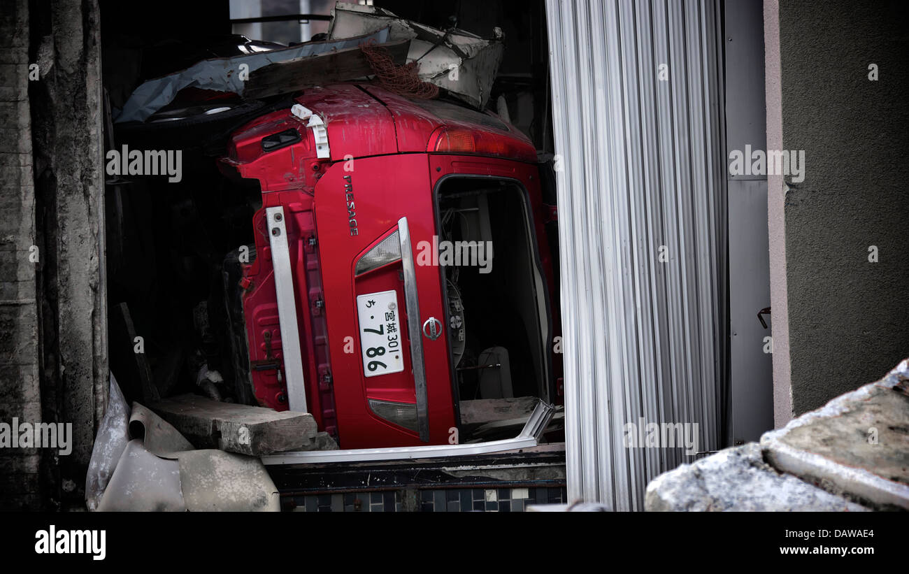 Une Nissan Prestige coincé sous les débris dans l'un des bâtiment renversé au quartier gravement endommagé Onagawa Banque D'Images