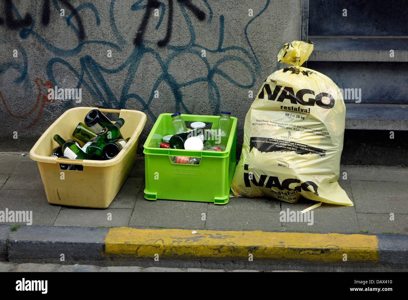 Les récipients en plastique avec des bouteilles en verre et sac à déchets avec les déchets ménagers en face de chambre en ville rue Banque D'Images