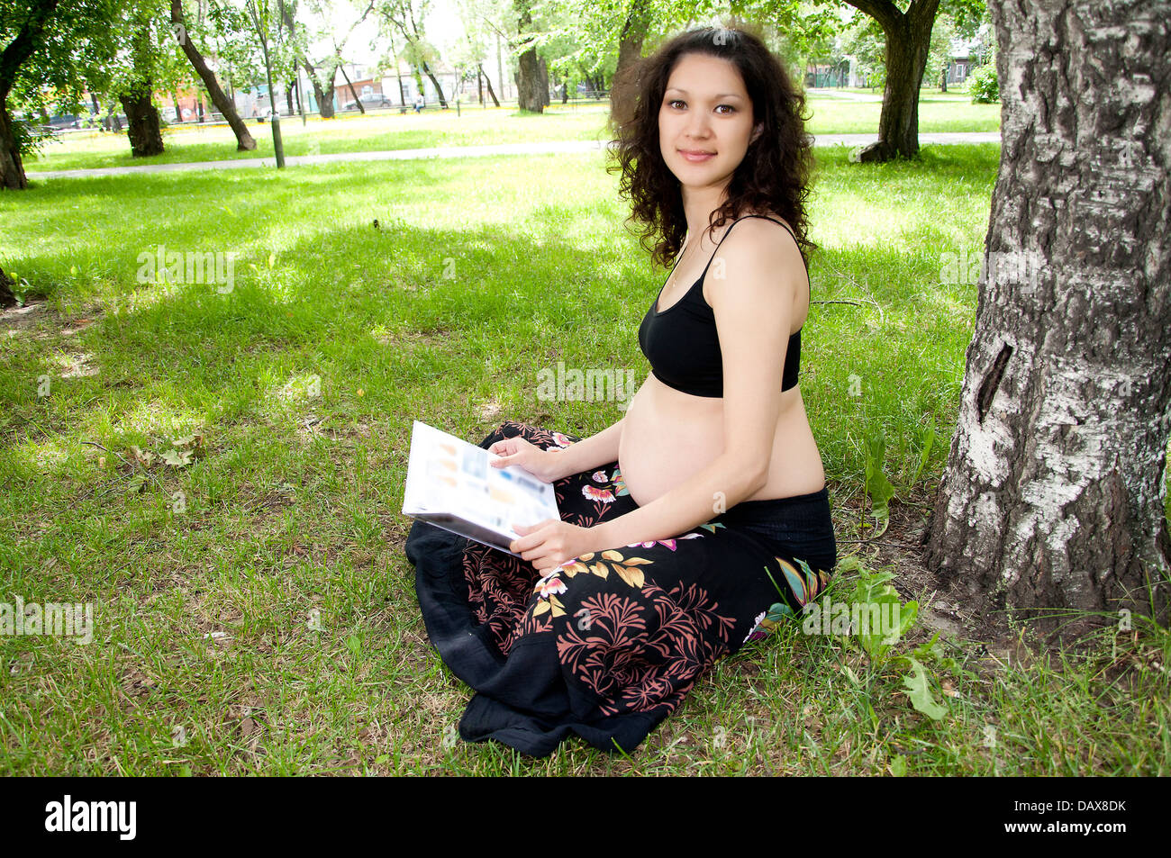 Belle femme enceinte lire livre dans le parc Banque D'Images