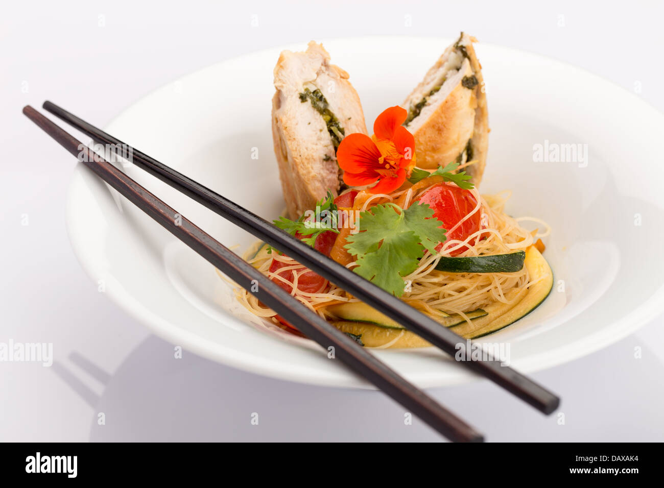 La cuisine asiatique avec des morceau de poulet farcies, les nouilles, les courgettes, les carottes et les tomates. Banque D'Images