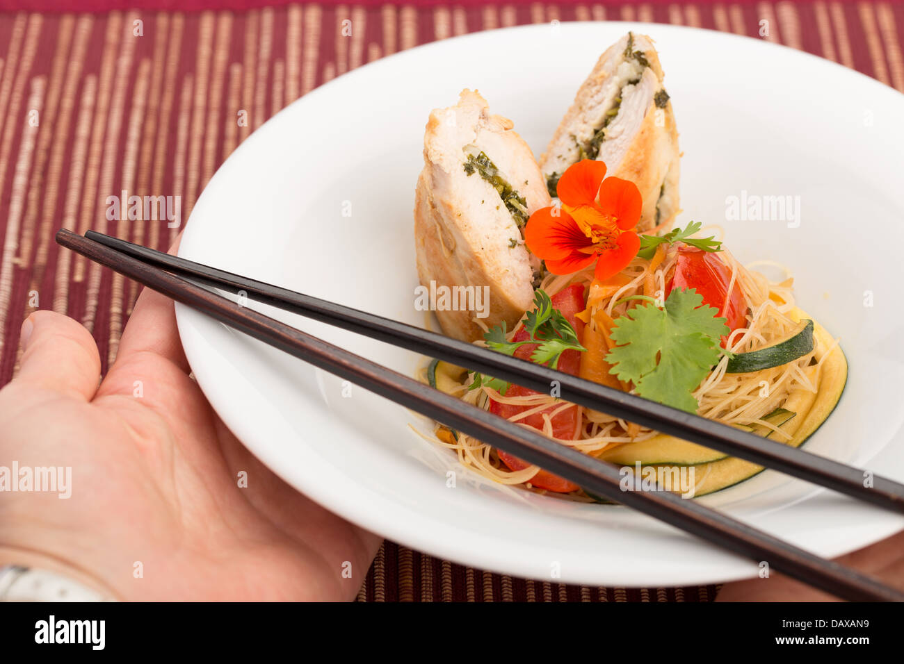 La cuisine asiatique avec des morceau de poulet farcies, les nouilles, les courgettes, les carottes et les tomates. Banque D'Images
