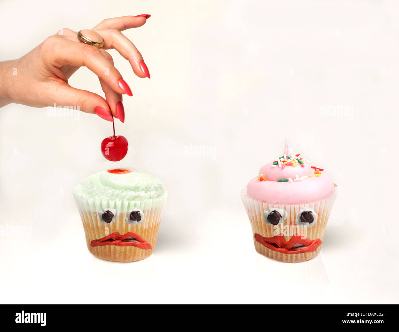 La main de femme une cerise d'un triste cupcake Banque D'Images